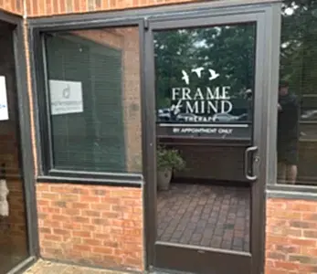 Glass door storefront with 'Frame of Mind Therapy' sign and bird graphic; reads 'BY APPOINTMENT ONLY' (entrance to therapy clinic).